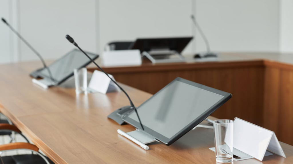 Modern meeting room with conferencing microphones and tabletop control screens
